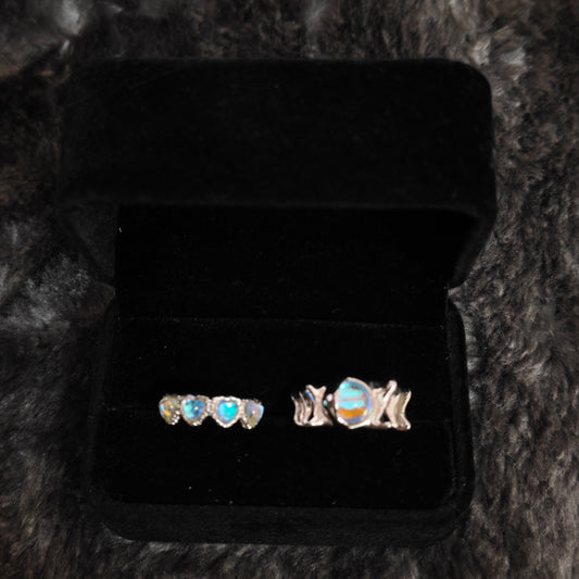 Two iridescent aurora rings displayed side by side in black velvet box, close-up detail view