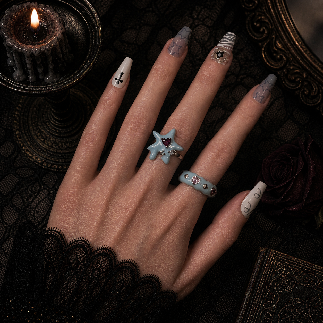 Baby blue enamel melting star ring with pink heart stone and blue enamel heart gem band worn on hand, dark gothic background