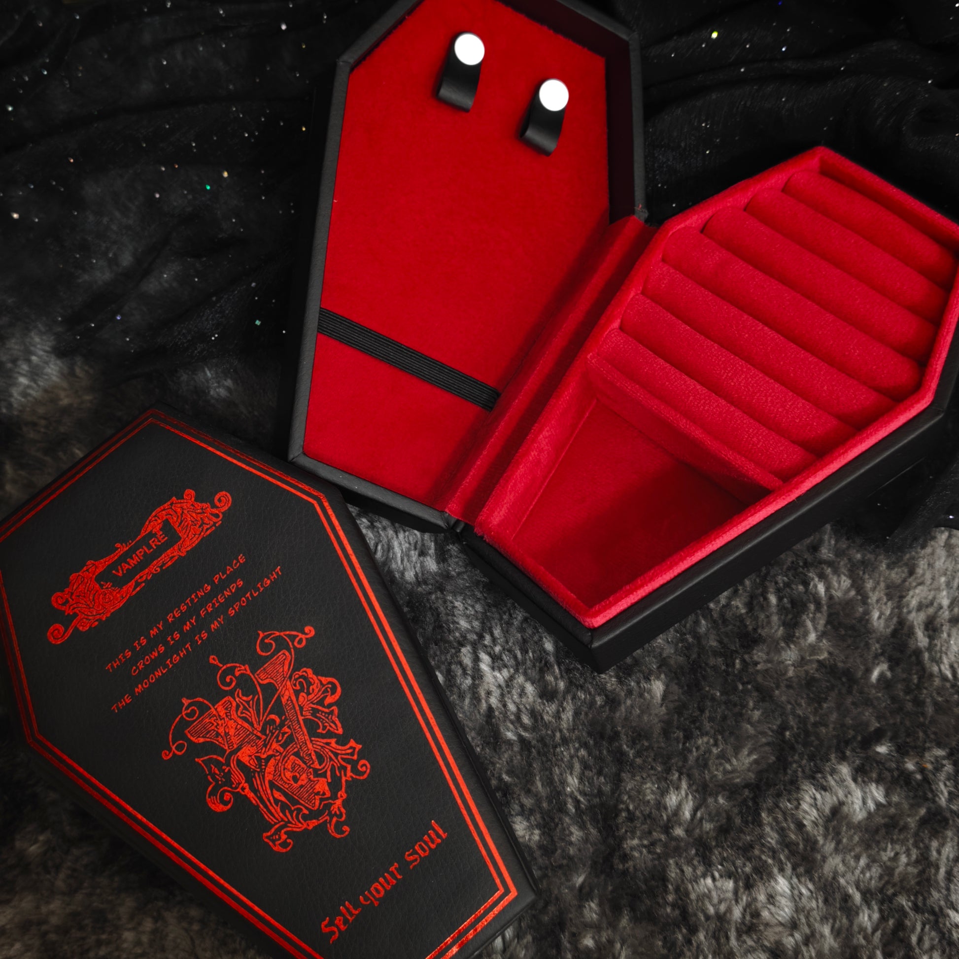 Gothic coffin jewelry box open showing red velvet interior with ring slots and stud earring holders, overhead view