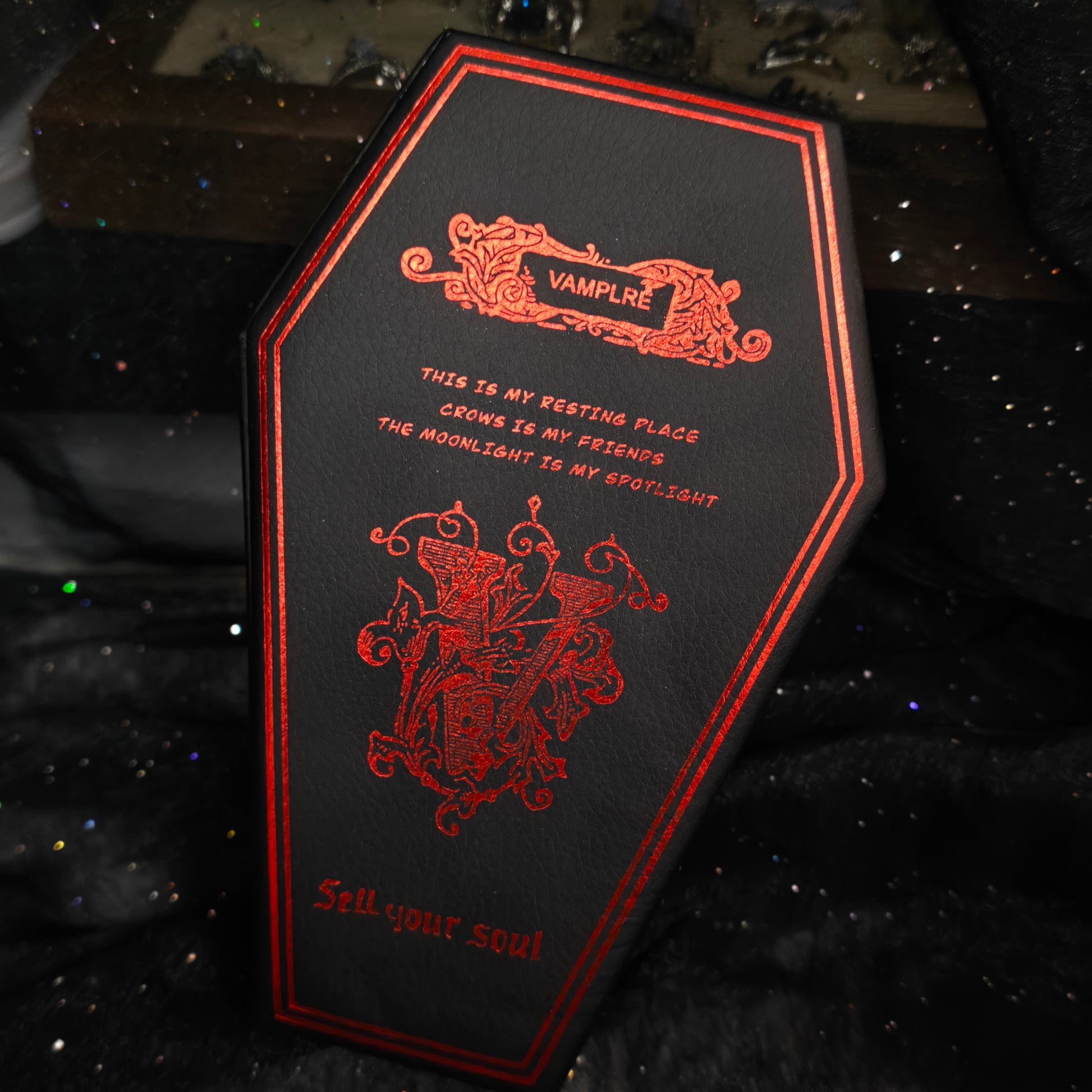 Black coffin jewelry box back panel with red foil crest and Sell Your Soul text on black glitter background