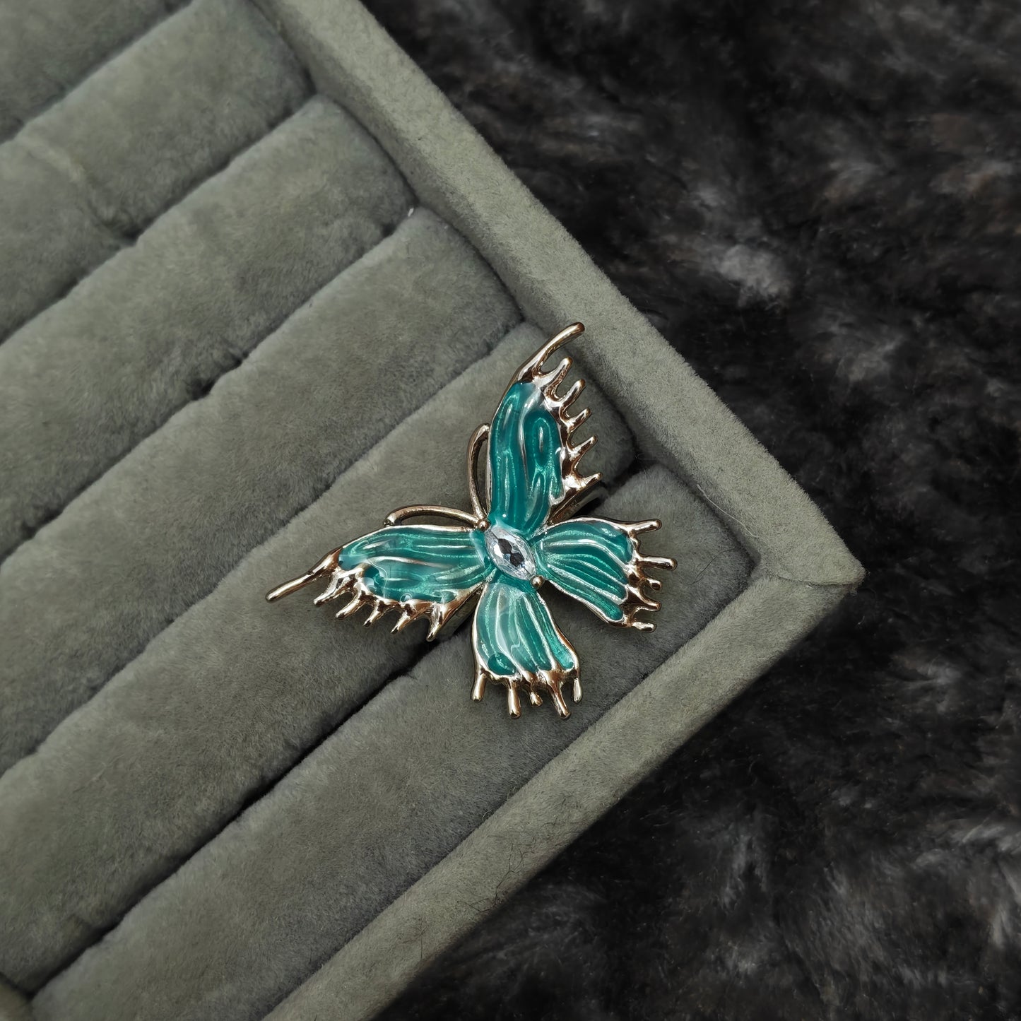 Single dark coquette ring displayed individually on grey velvet, macro product photo