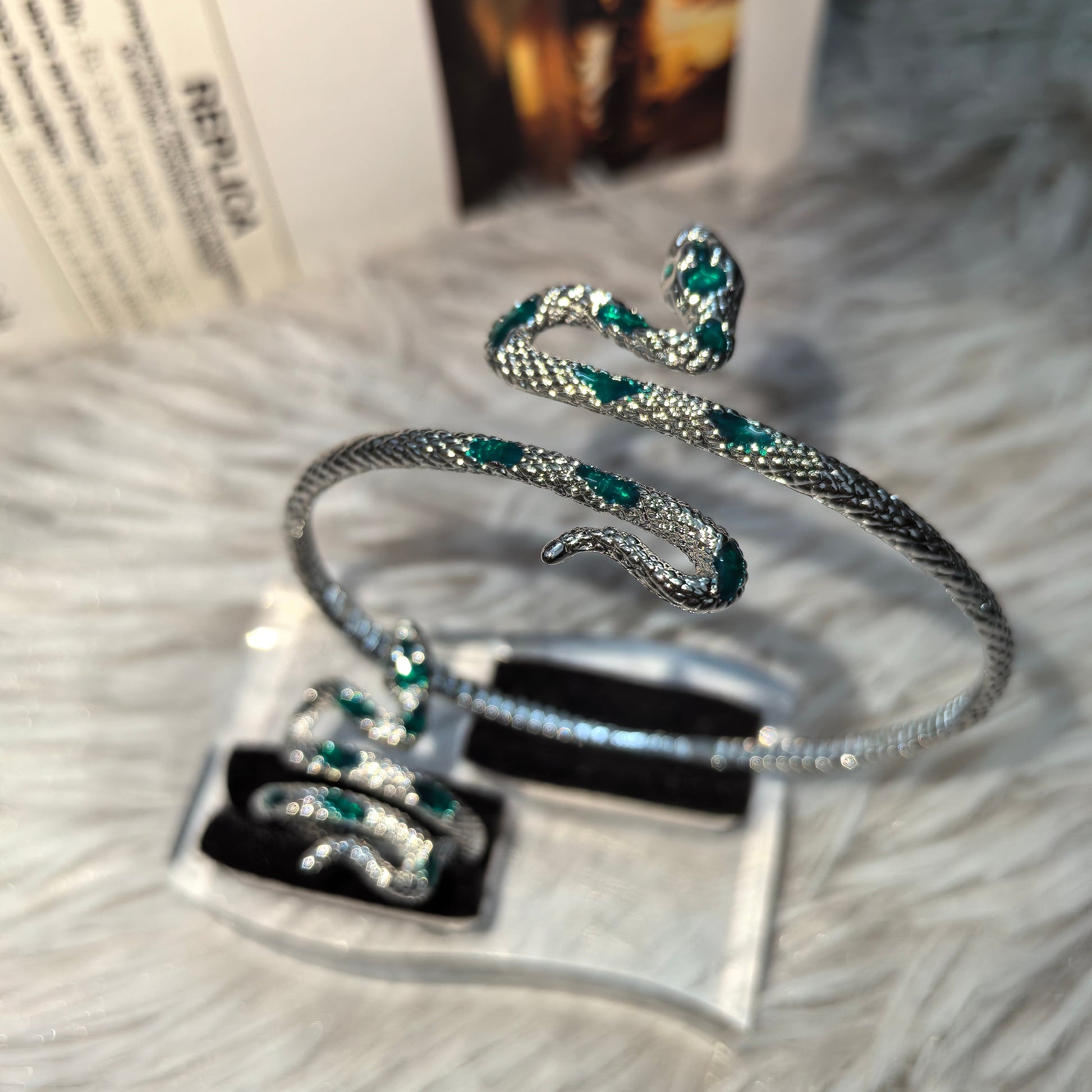 Silver bracelet with emerald green stones on a textured surface