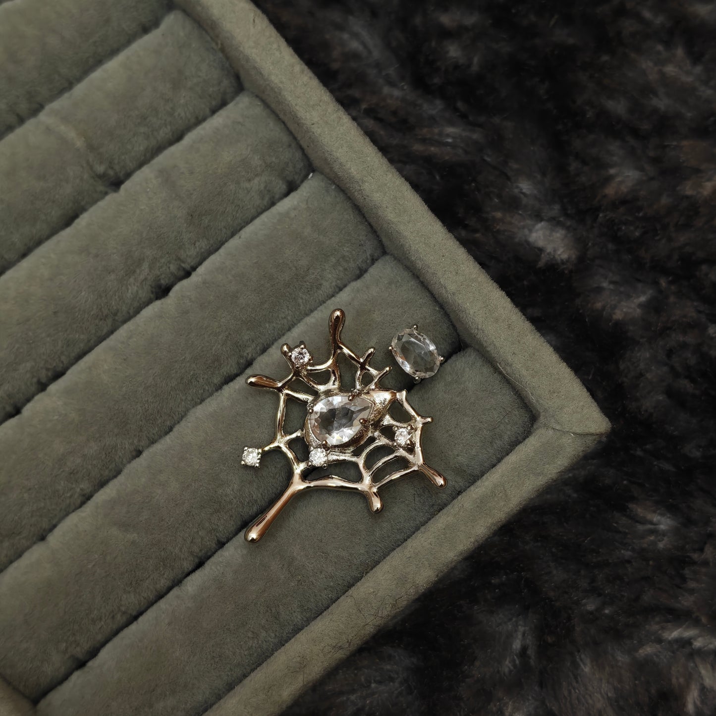 Individual grunge statement ring shown alone on grey velvet, angled close-up view