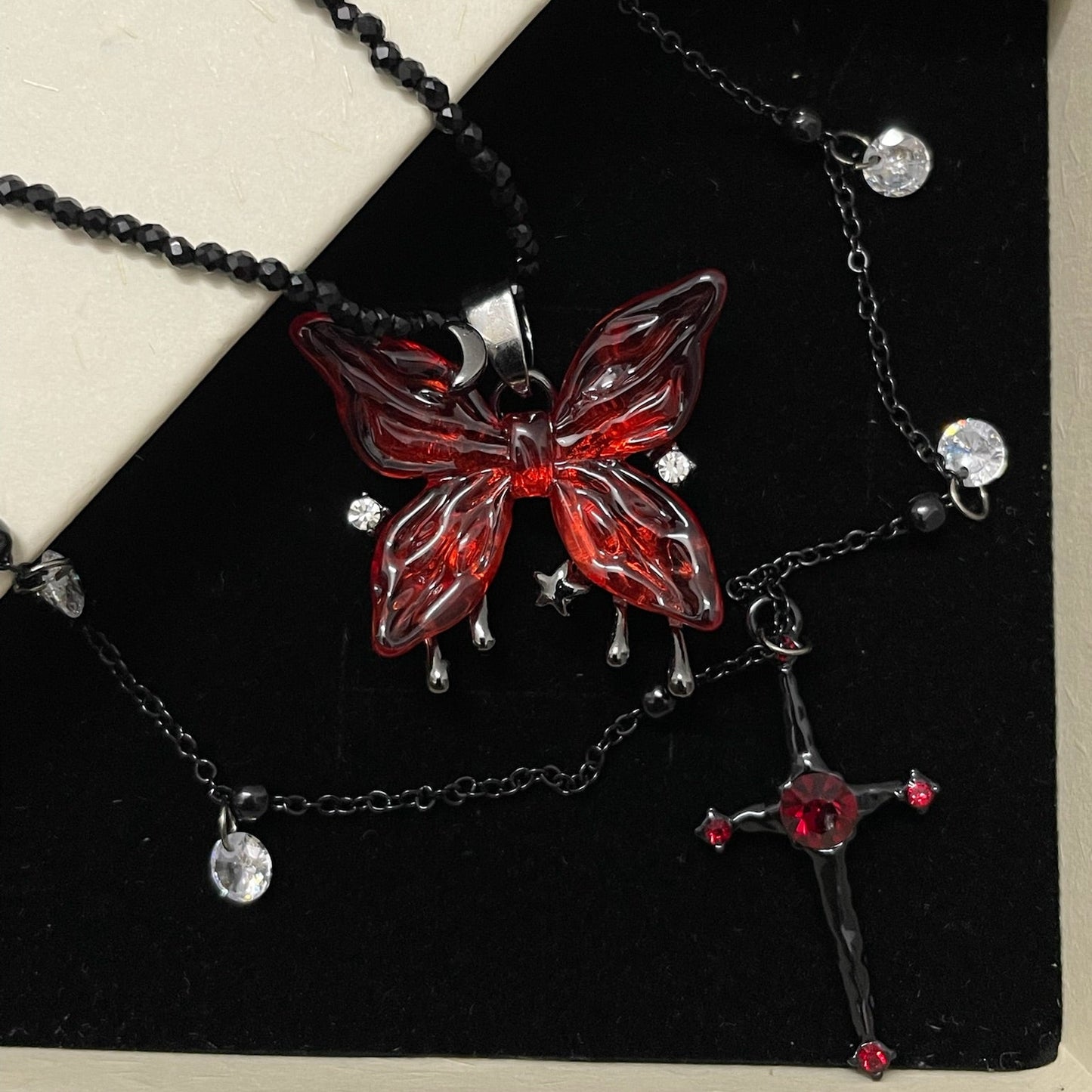Blood Rose Butterfly & Gothic Cross Necklace in open black velvet jewelry box, angled view