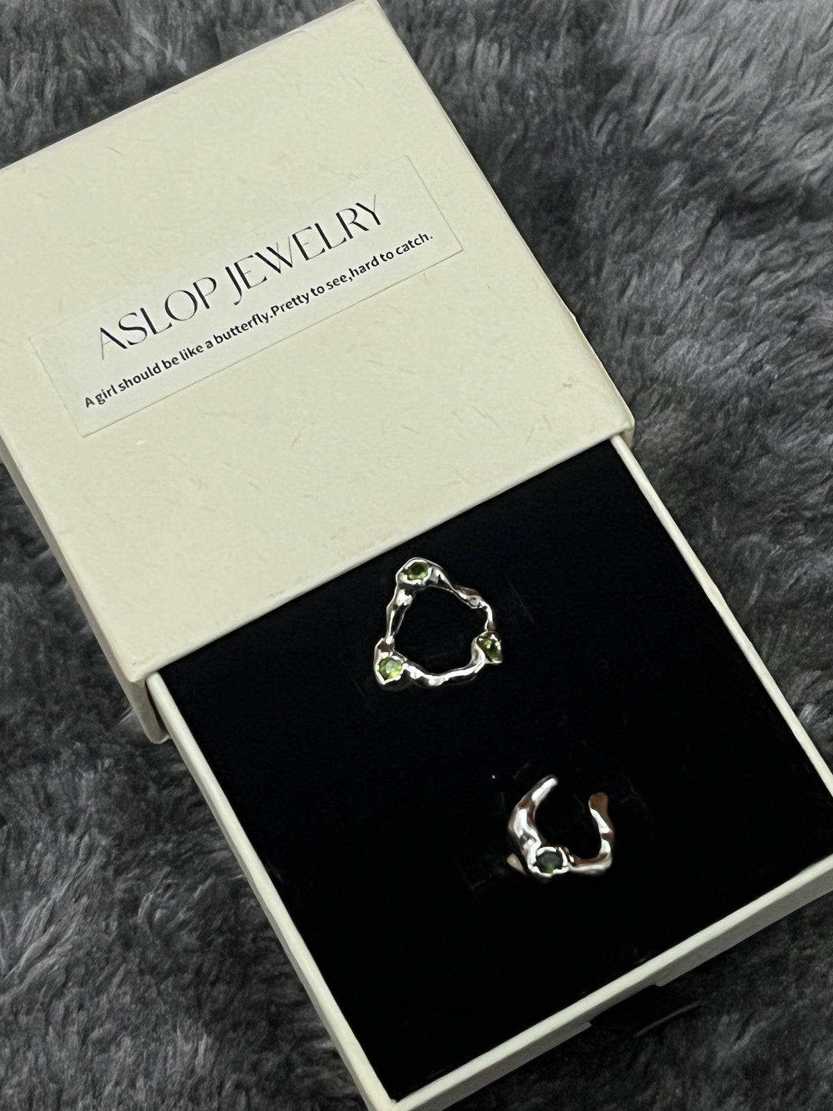 Crisscross Emerald Ring in 3-Stone and 1-Stone styles, close-up on black velvet display