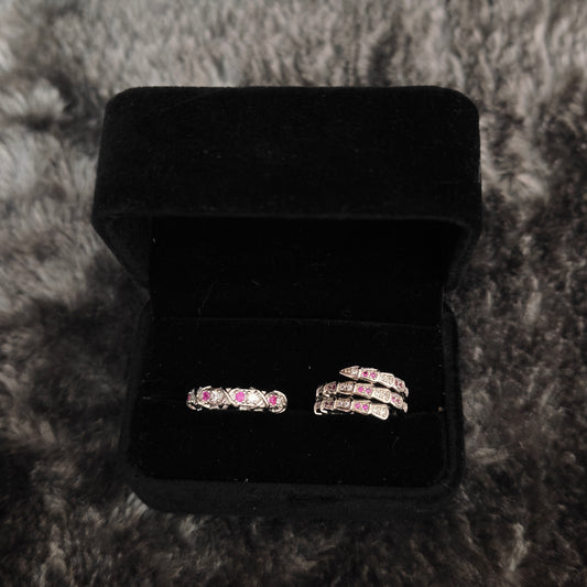 Two silver rings with pink and clear stones in open black velvet box, overhead flat view