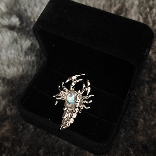 Silver sculptural scorpion ring with aurora stone in open black velvet jewelry box, angled view