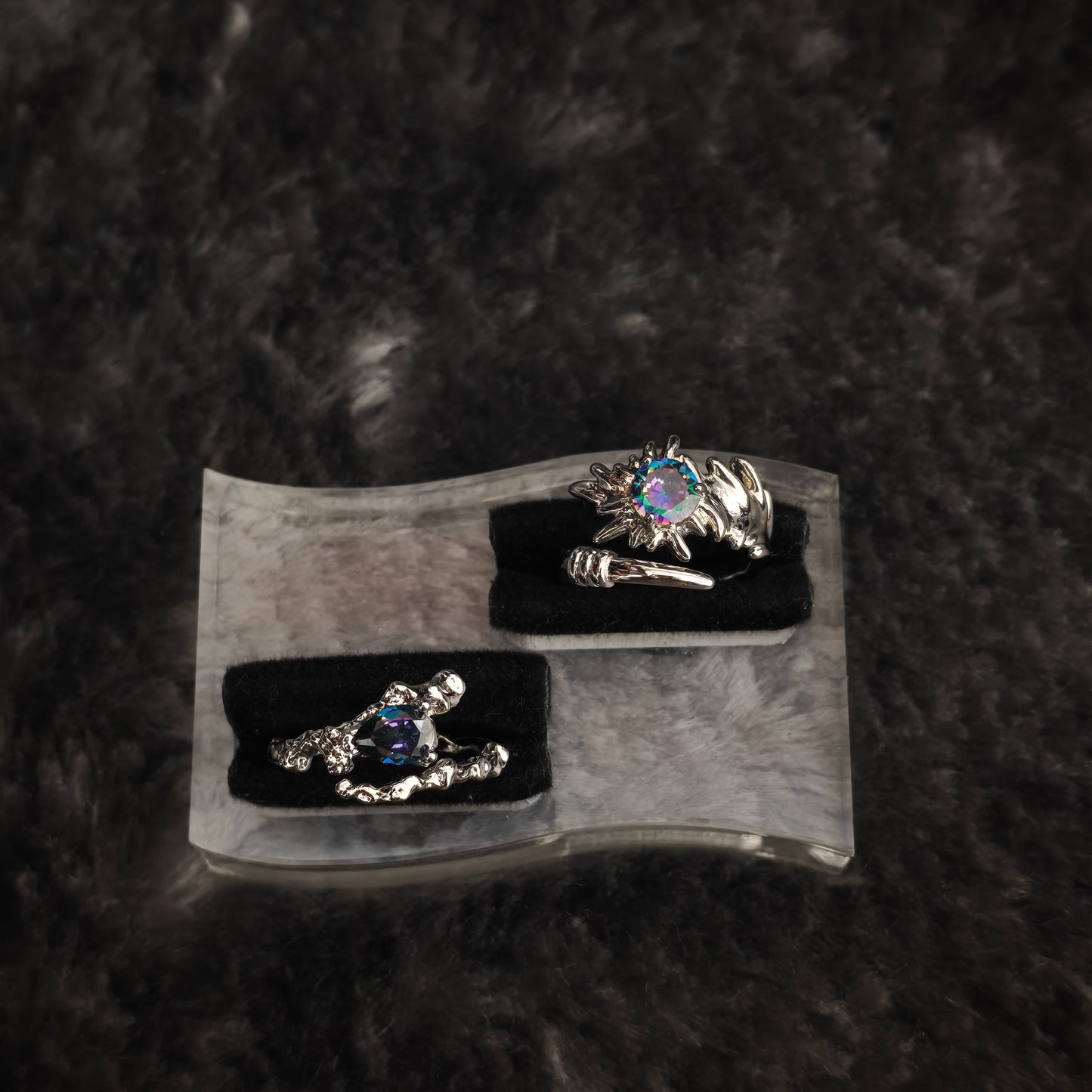 Silver aurora claw ring with iridescent round stone on black velvet display, tilted angle showing spiked detail and adjustable band
