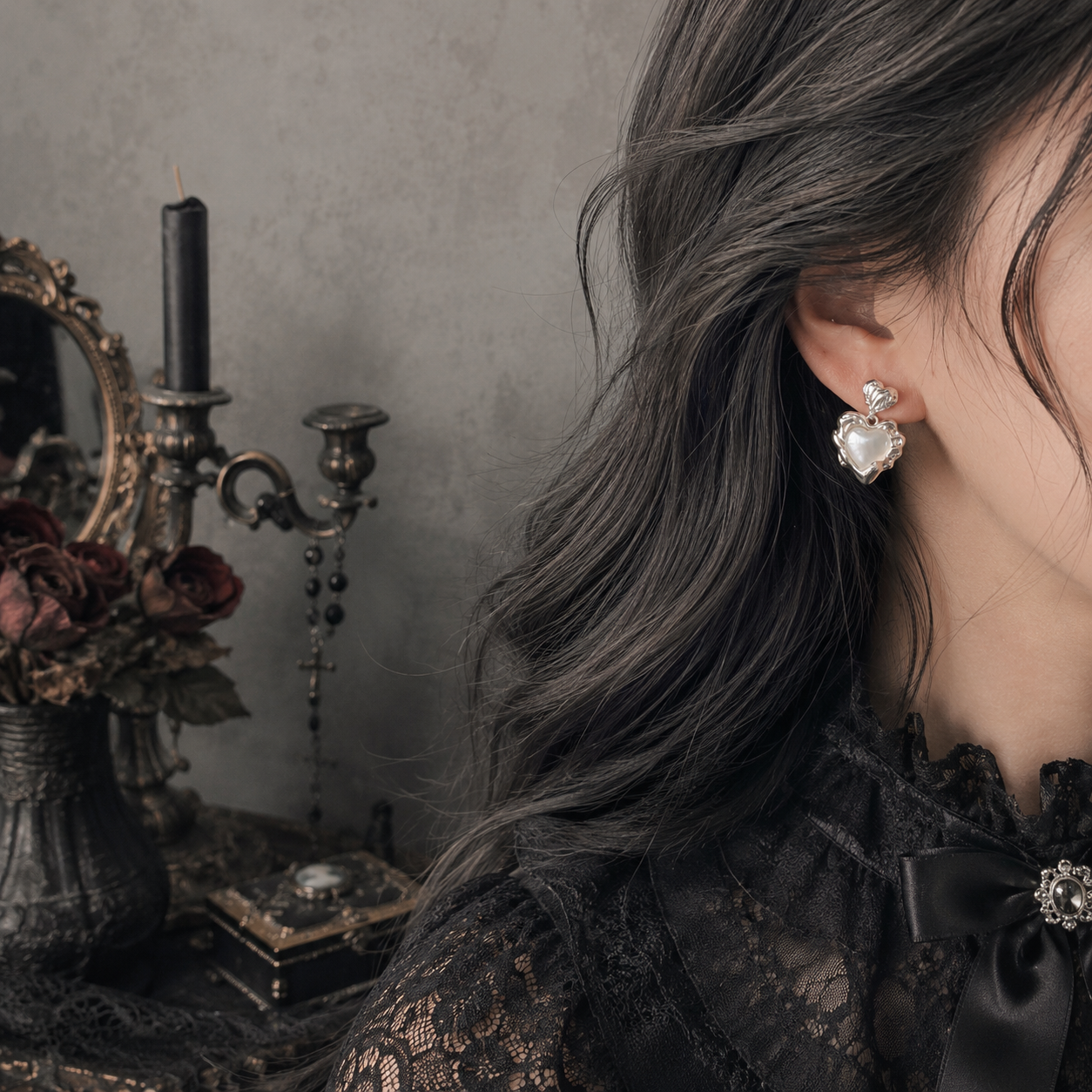 Silver and gold baroque sacred heart pearl drop stud earrings displayed side by side on grey stone surface, both colourways