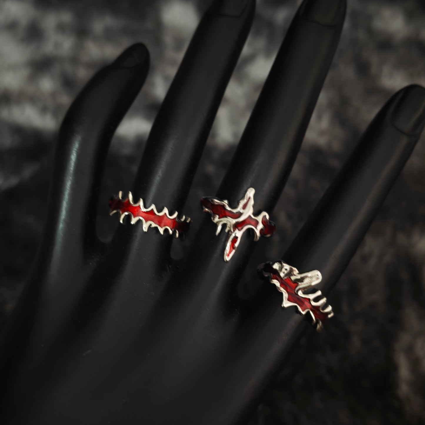 Three red enamel blood drip stacking rings in black velvet box, overhead flat view
