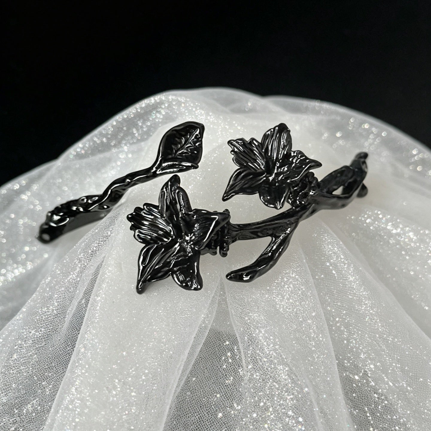All-black open cuff bracelet with sculptural datura flower blooms and thorn branch