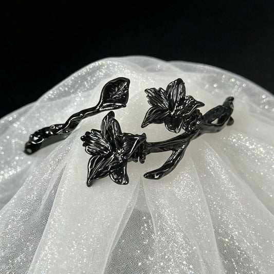All-black open cuff bracelet with sculptural datura flower blooms and thorn branch
