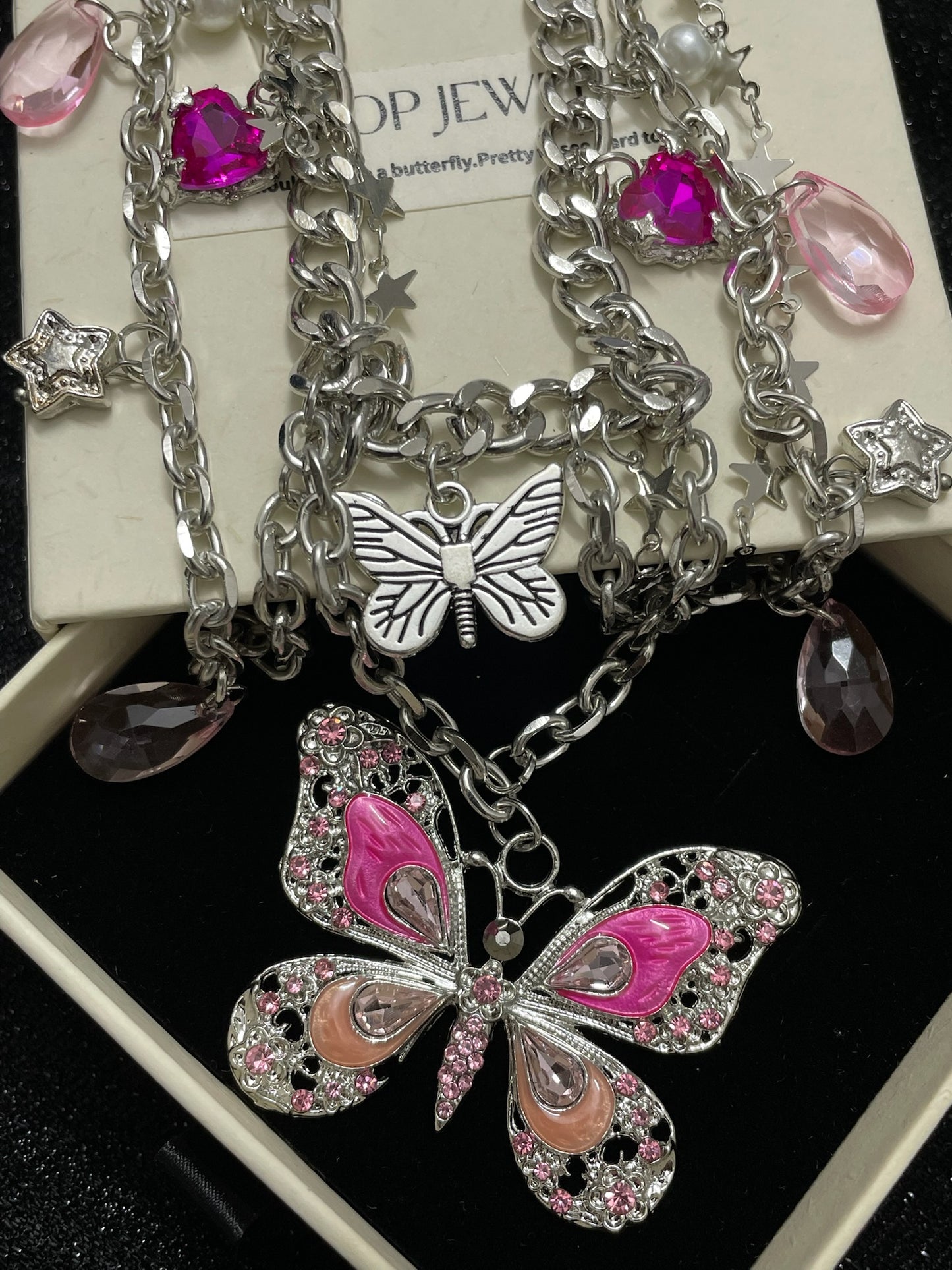 Pink Butterfly Charm Necklace in open black velvet jewelry box, overhead flat lay