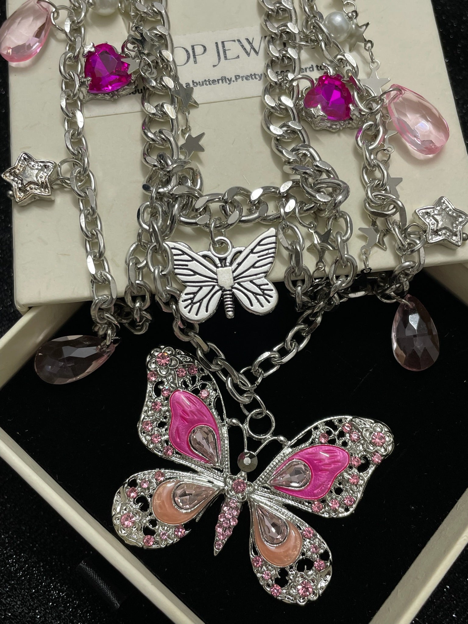Pink Butterfly Charm Necklace in open black velvet jewelry box, overhead flat lay