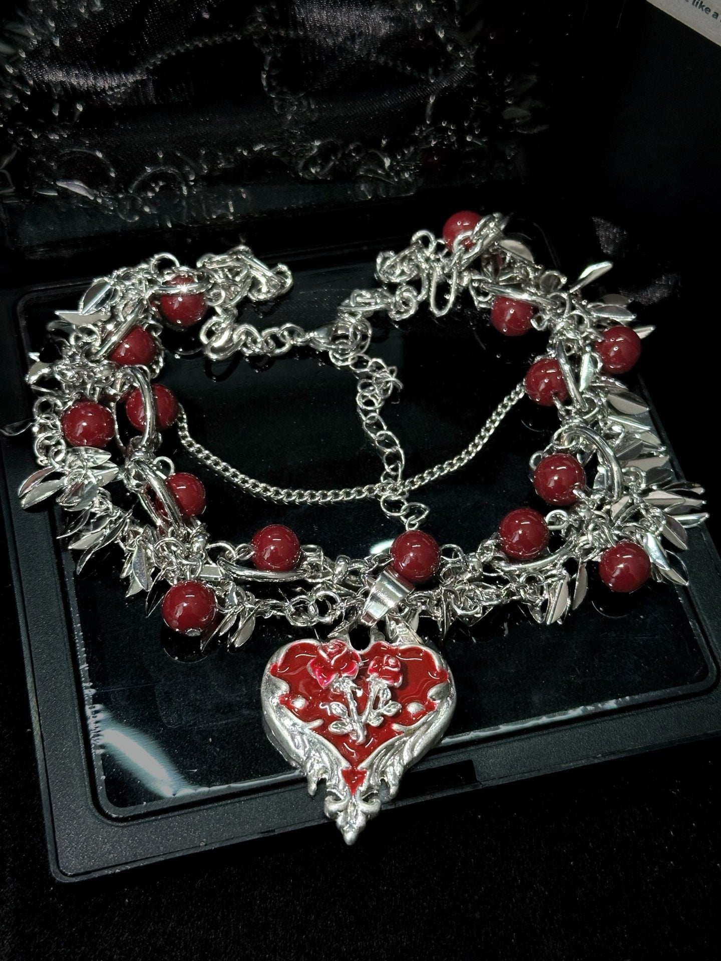 Dark Romance Rose Heart Necklace in open black velvet jewelry box, angled view