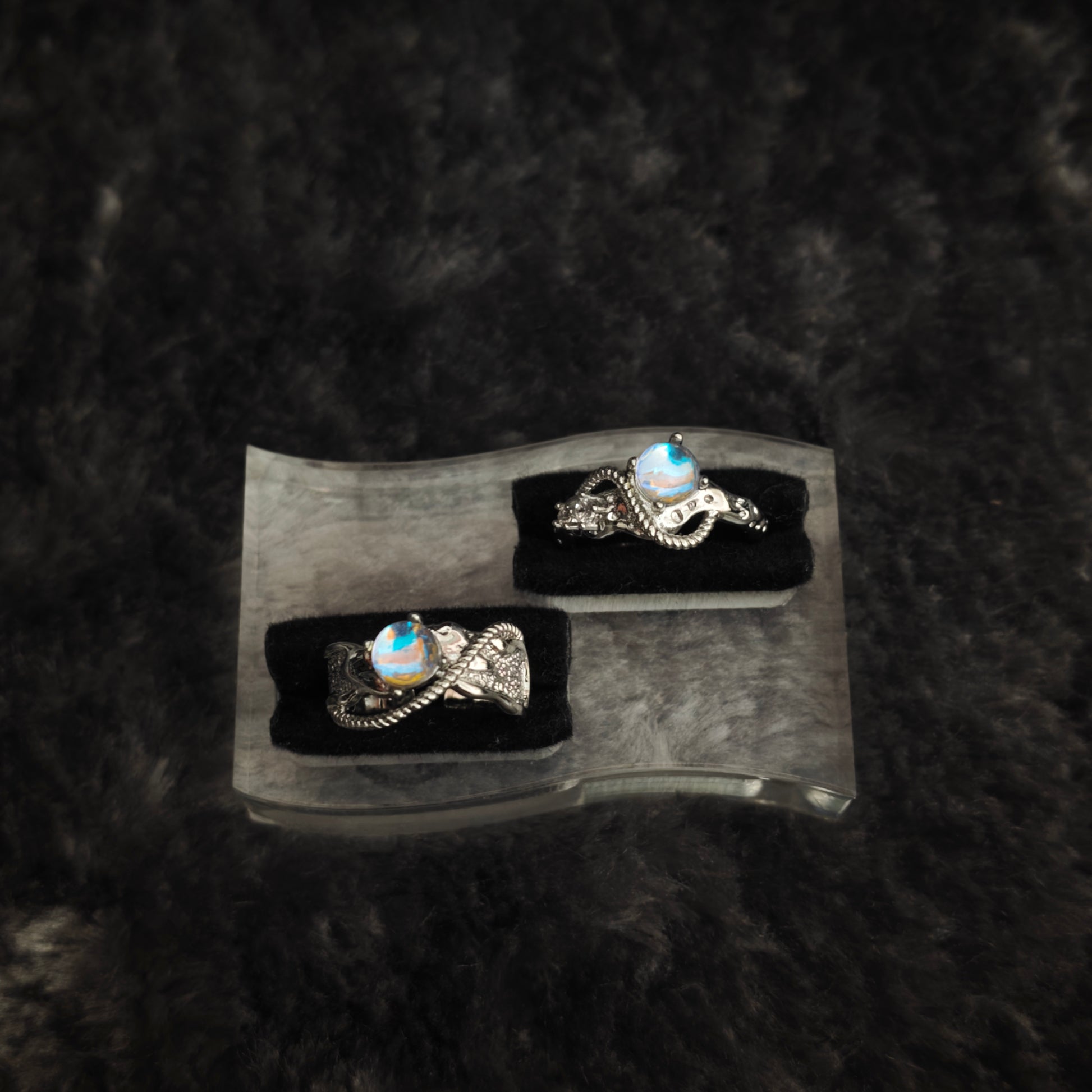 Silver arc ring set displayed on clear acrylic stand, diagonal overhead view