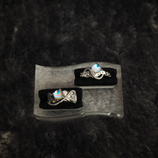 Silver arc ring set displayed on clear acrylic stand, diagonal overhead view