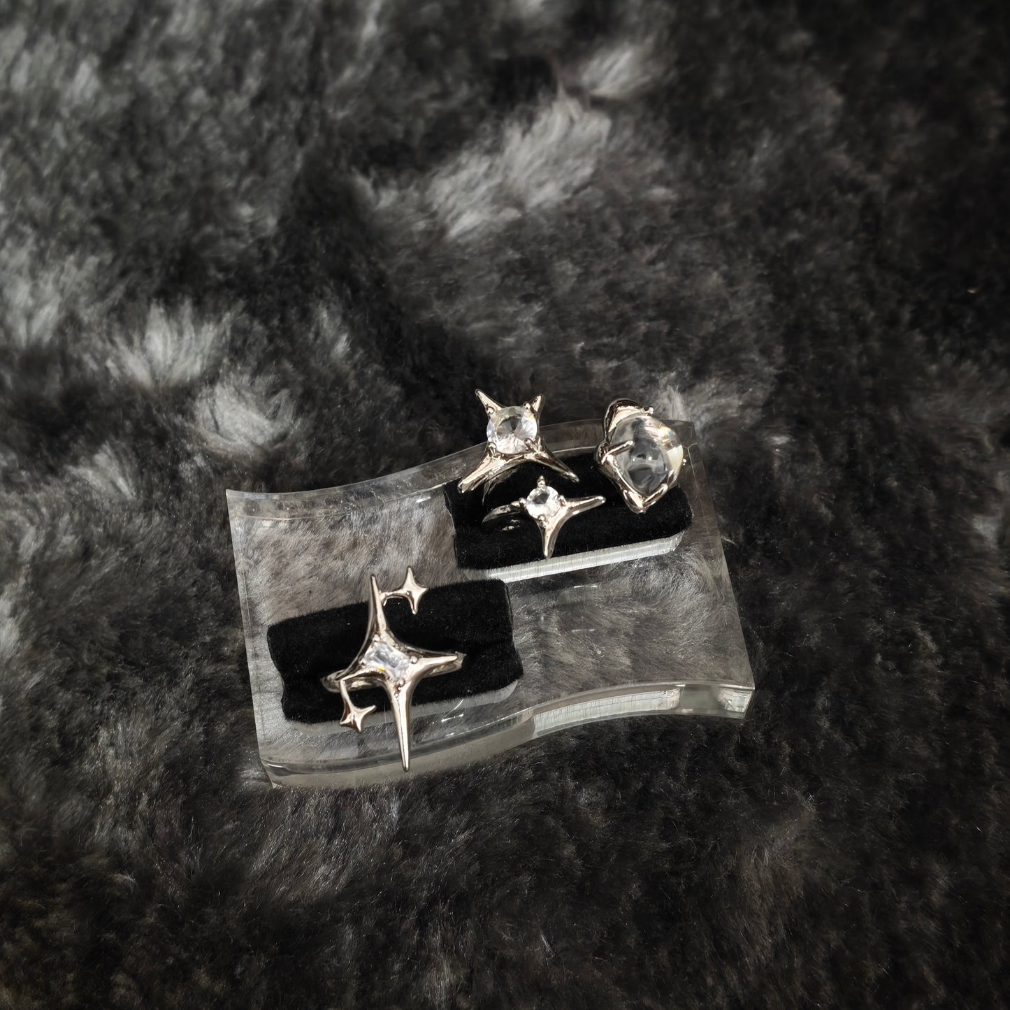 Silver four-pointed star spike ring set with clear stones displayed on black velvet slots, close-up flat view