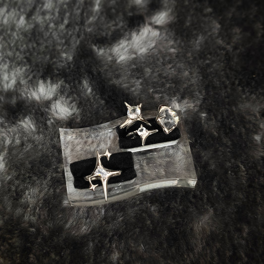Silver four-pointed star spike ring set with clear stones displayed on black velvet slots, close-up flat view